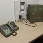 Askerlikte kontrollü telefon kullanımını temsil eden sade asker koğuşu masası